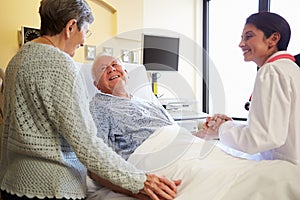 Female Doctor Talking To Senior Couple In Hospital Room