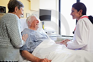 Female Doctor Talking To Senior Couple In Hospital Room