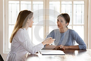 Female doctor therapist consulting young woman at medical appointment