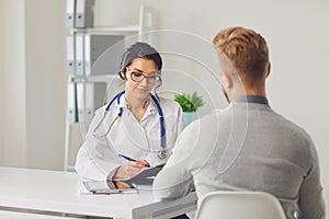 Female doctor therapist gross allergist nutritionist otolaryngologist and male patient sitting at a table in a clinic