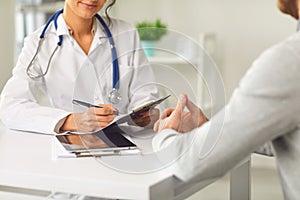 Female doctor therapist gross allergist nutritionist otolaryngologist and male patient sitting at a table in a clinic photo