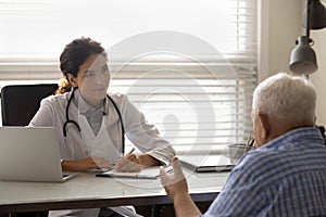 Female doctor therapist listening to patient complaints, filling form