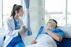 Female doctor treating young male patient in bed and talking with Asian male patient beside bed