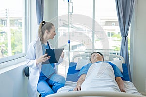 Female doctor treating young male patient in bed and talking with Asian male patient beside bed