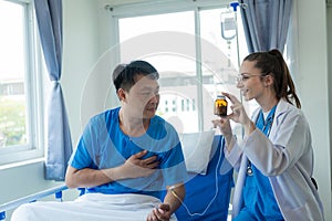 Female doctor treating young male patient in bed and talking with Asian male patient beside bed