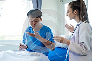 Female doctor treating young male patient in bed and talking with Asian male patient beside bed