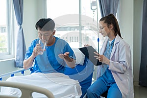 Female doctor treating young male patient in bed and talking with Asian male patient beside bed