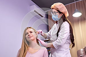 female doctor trichologist conducts mesotherapy or plasma therapy for young woman patient