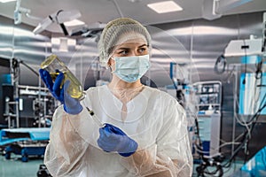 female doctor in uniform face mask in gloves prepares syringe with antibiotic in operating