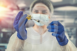 female doctor in uniform face mask in gloves prepares syringe with antibiotic in operating