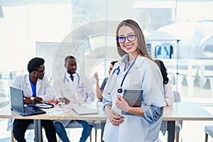 Female doctor uses tablet computer in hospital conference room. Professional female doctor in white medical uniform at