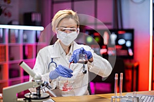 Female doctor using microscope with vacuum tubes for samples with COVID 19 infection