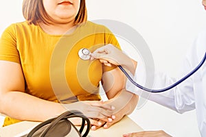 Female doctor using stethoscope checking the pulse of obese patients in the hospital.