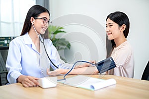 A female doctor using stethoscope to check patient's heartbeat and blood pressure at hospital. Medical and health concept