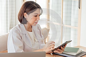 A female doctor is using a tablet to analyze the symptoms of a patient in the office