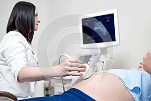 Female doctor using ultrasound and screening pregnant woman.