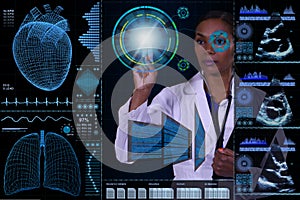 A female doctor is visible behind a futuristic computer floating in front of her.