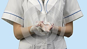 Female doctor washing his hands with soap foam.