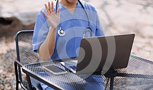 Female Doctor Wearing Scrubs In Hospital Corridor Using Digital Tablet