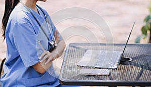 Female Doctor Wearing Scrubs In Hospital Corridor Using Digital Tablet