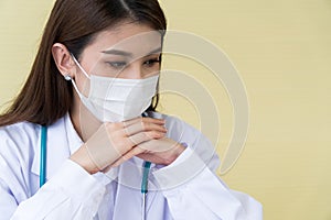 The female doctor wearing a surgical mask is thinking and looking down with a yellow background