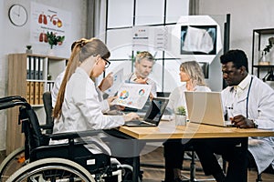 Female doctor in wheelchair working multiracial colleagues