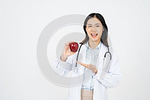 Female doctor with a white coat smiling and holding an apple