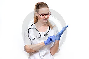 Female doctor in white coat with stethoscope puts on gloves. Isolated on white background. Young beautiful woman