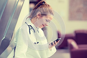 Female doctor in white lab coat using mobile smart phone