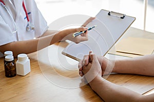 A female doctor in a white nurse is consulting her patient. while sitting in the office Female doctor holding a pen to fill patien