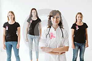 Female doctor in white uniform with pink bow standing in front of patients