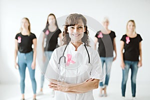 Female doctor in white uniform with pink bow standing in front of patients