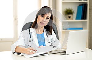 Female doctor working feeling up prescription and medical records with clipboard and laptop office