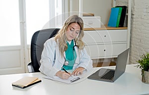 Female doctor working feeling up prescription and medical records with clipboard and laptop office