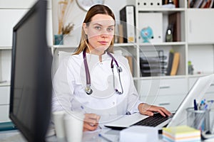 Female doctor working on laptop in clinic office