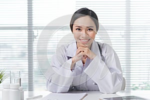 Female doctor working at office desk and smiling