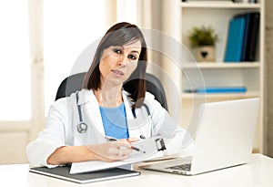 Female doctor working with stethoscope and clipboard in medical office with serious face expression