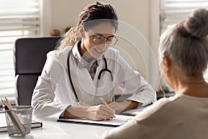 Female doctor write prescription to elderly patient