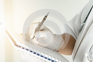 Female doctor writing medical information in notebook at hospital