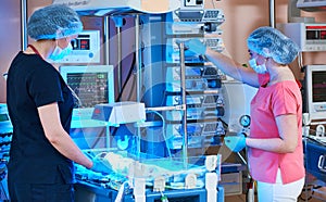 Female doctors in front of intensive care unit for newborn infant baby