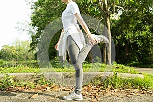 Female doing stretching exercise for legs, Young fitness healthy woman warm up before running or jogging in the park in sunshine