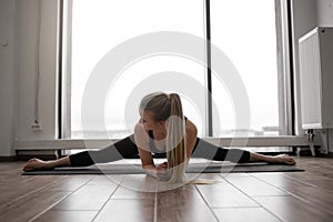 Female doing Upavistha Konasana during workout in studio