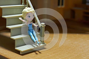 Female doll sits on stair of doll house
