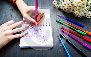 Female drawing flower shapes in notebook