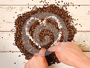 Female drawing a heart symbol in the pile of organic buckwheat husks on a wooden planks background