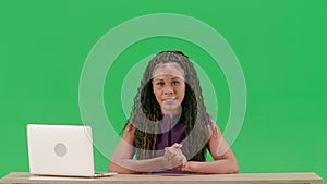 Female in dress sit at the desk isolated on chroma key green screen background. African american woman tv news host