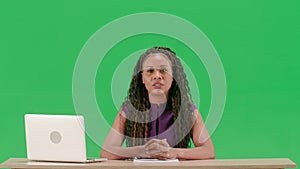 Female in dress sit at the desk isolated on chroma key green screen background. African american woman tv news host