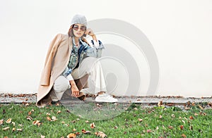 Female dressed fashion multilayered autumn outfit posing at camera near the white wall