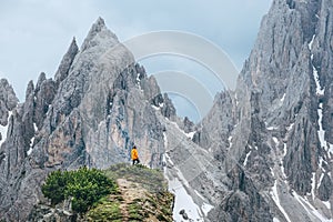 Female dressed orange bright jacket on the green mountain hill enjoying picturesque Dolomite Alps range peaks view near the Giau