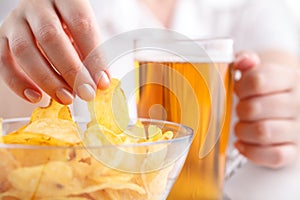 Female drink beed and eat heap of potato chips